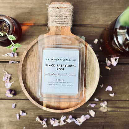 Bottle of N.E. Love Naturals, LLC Black Raspberry + Rose product on a wooden surface with decorative elements.
