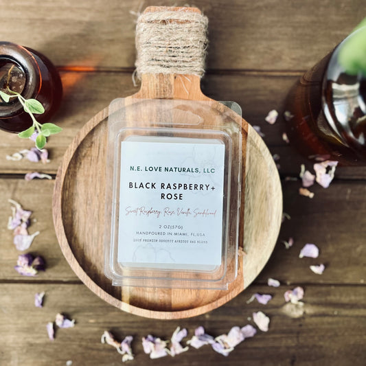 Bottle of N.E. Love Naturals, LLC Black Raspberry + Rose product on a wooden surface with decorative elements.