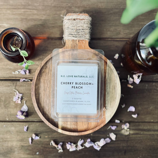 Wax Melt labeled 'Cherry Blossom + Peach' by N.E. Love Naturals on a wooden surface with decorative elements.